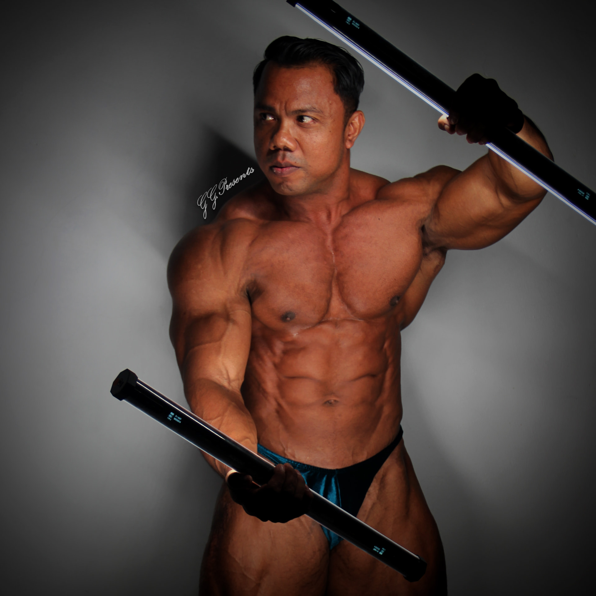 Muscular athlete posing with two illuminated light sabres in studio